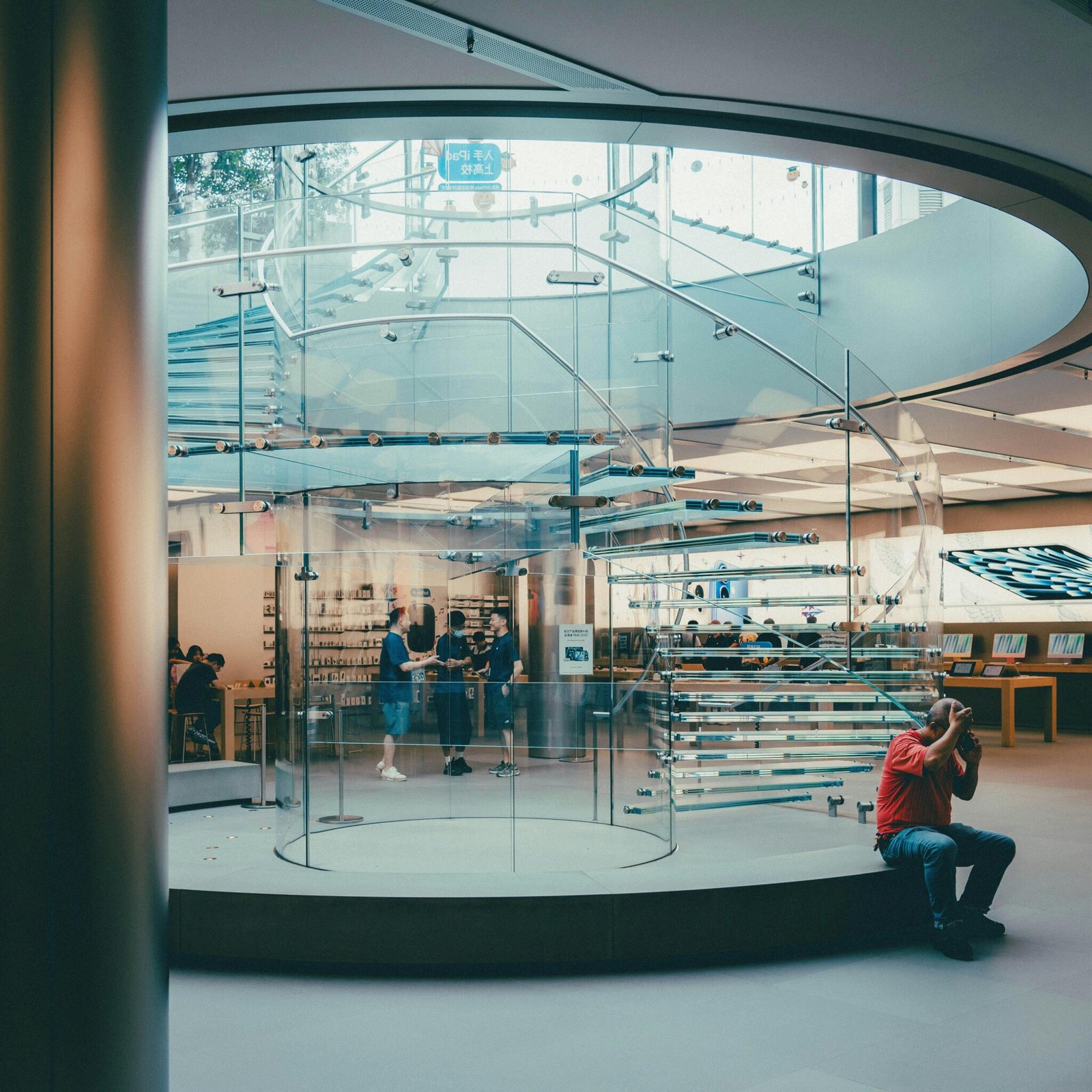 Elegant glass spiral staircase in a contemporary retail store interior.